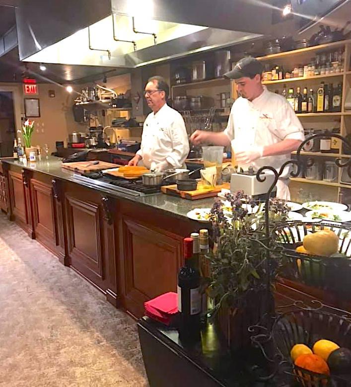 Head chef and assistant chef entertaining guests with cooking demonstrations on a stage kitchen 