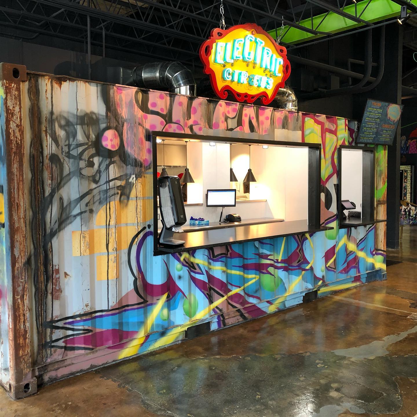 Precarious Beer Hall food stand serving tacos and nachos from an indoor converted shipping container featuring colorful street-style graffiti 