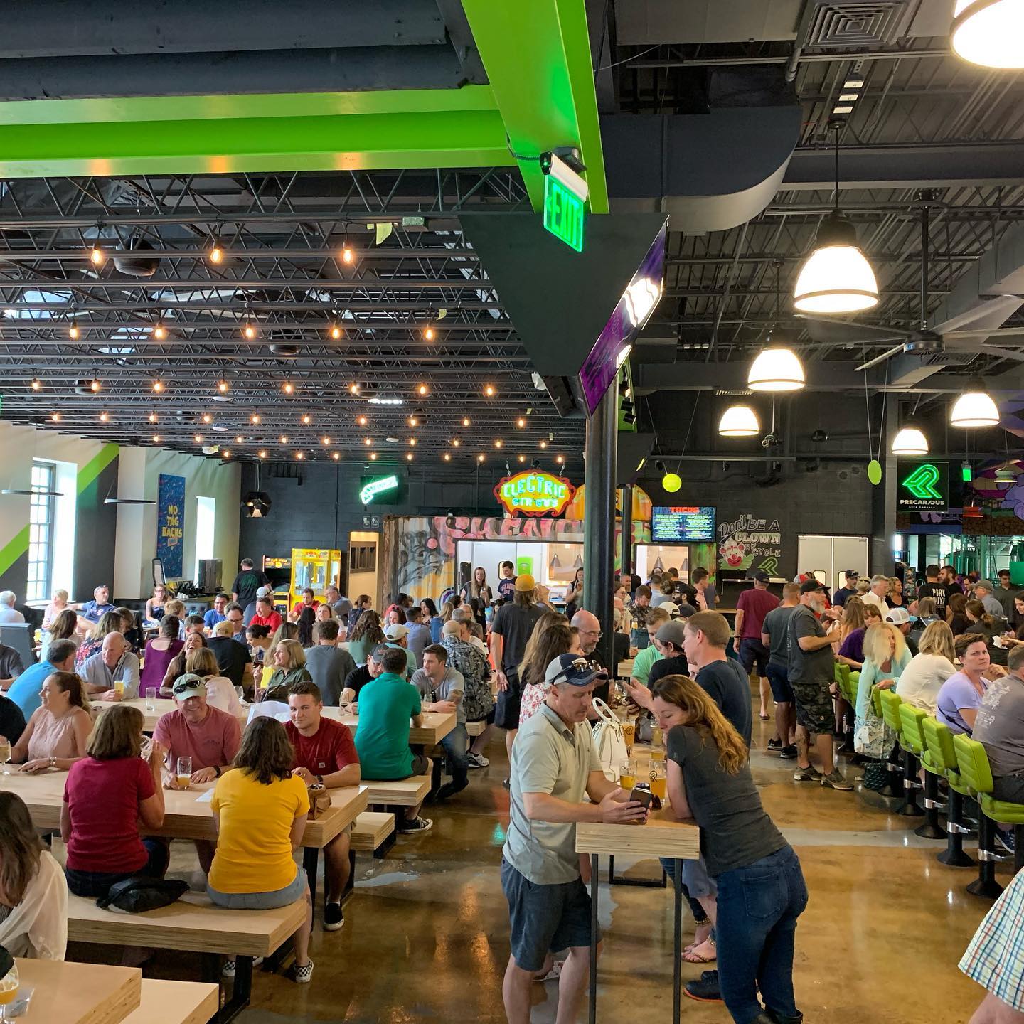 Precarious Beer Hall restaurant featuring guests seated at communal style tables surrounded by colorful decor and architecture